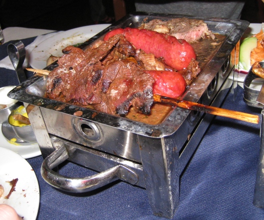 A mixed grill of anticuchos, chorizo, and steak.